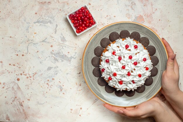 Vue de dessus du gâteau avec de la crème pâtissière et du chocolat dans une baie de main féminine dans un bol