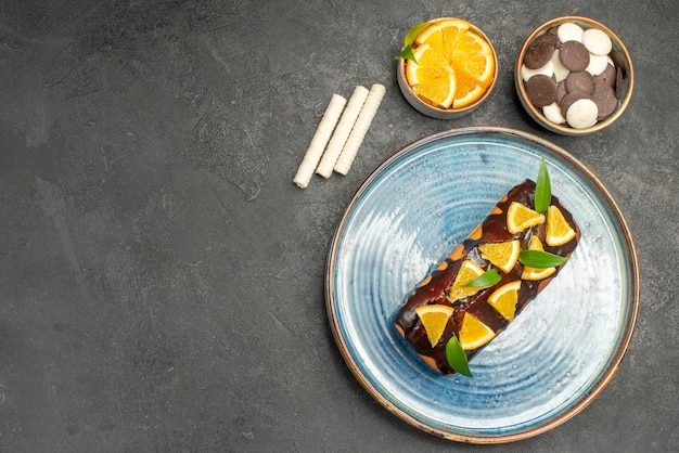 Vue de dessus du gâteau moelleux décoré d'orange et de chocolat sur table noire