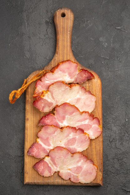 Vue de dessus du jambon tranché sur un bureau en bois et le fond gris