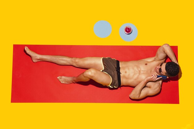 Vue de dessus du jeune mannequin caucasien reposant sur la station balnéaire sur tapis rouge et jaune