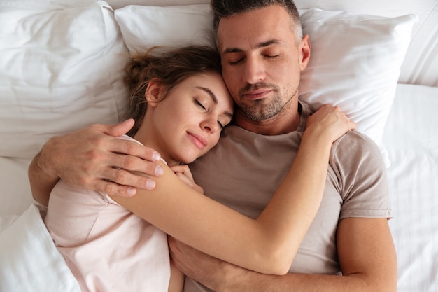 Vue de dessus du joli couple d'amoureux dormir ensemble dans son lit à la maison