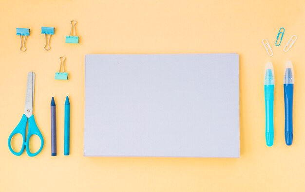 Vue de dessus du journal; des crayons de couleur; ciseaux et trombones disposés sur du papier de couleur