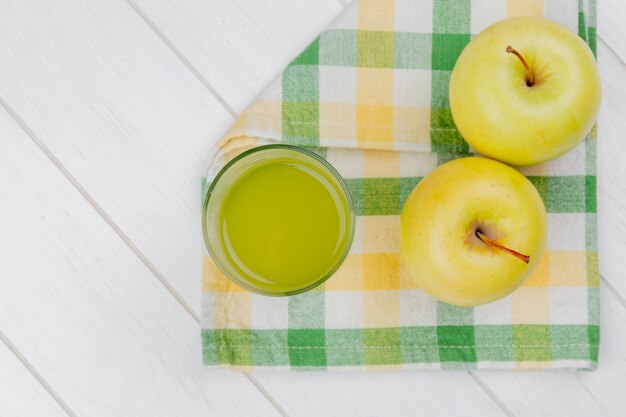 Vue de dessus du jus de pomme et pommes vertes sur tissu à carreaux et fond en bois avec espace copie