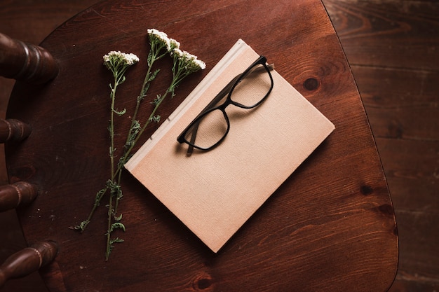 Photo gratuite vue de dessus du livre, des fleurs et des lunettes