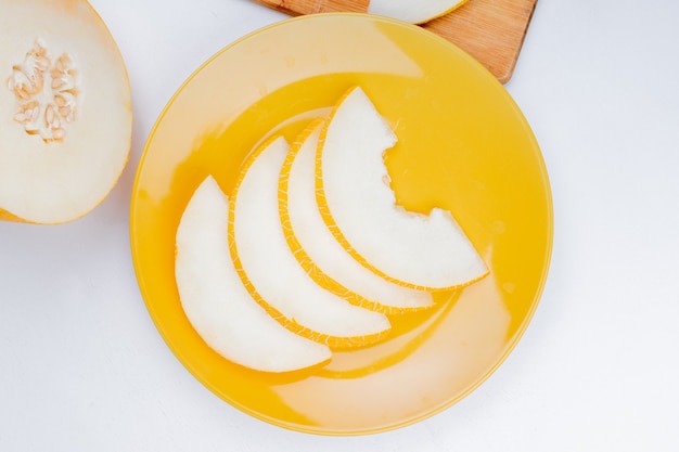 Vue de dessus du melon en tranches dans la plaque et en couper un sur fond blanc