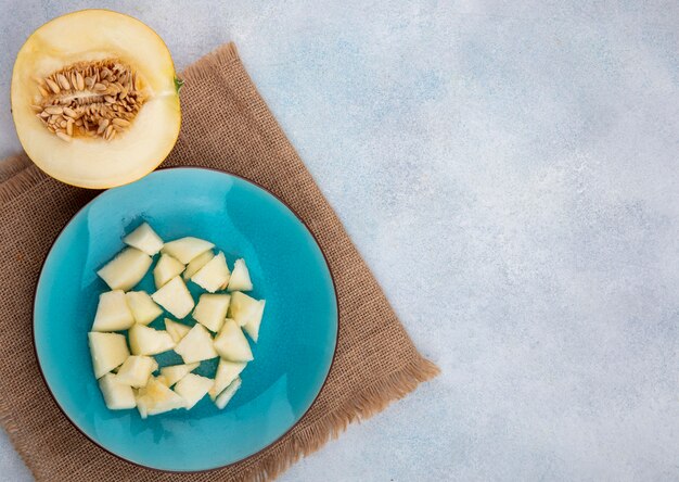 Vue de dessus du melon en tranches sur une plaque bleue sur toile de sac sur une surface blanche