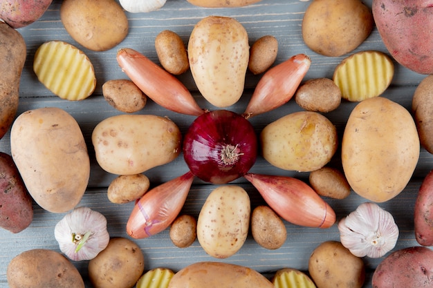 Vue de dessus du motif de légumes comme l'ail et l'oignon échalote de pomme de terre en tranches et sur fond de bois