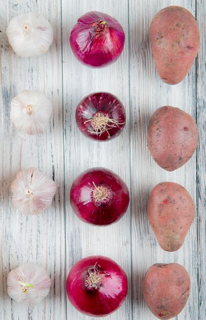 Vue de dessus du motif de légumes comme la pomme de terre oignon rouge ail sur fond de bois