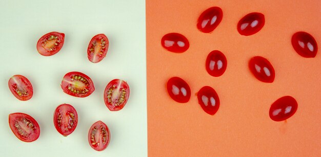 Vue de dessus du motif de tomates entières et coupées sur une surface blanche et orange