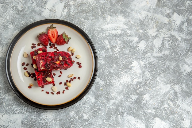 Vue de dessus du nougat rouge tranché avec des noix et des fraises rouges fraîches sur une surface blanche