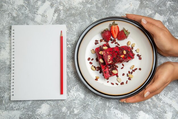 Vue de dessus du nougat rouge tranché avec des noix et des fraises rouges fraîches sur une surface blanche