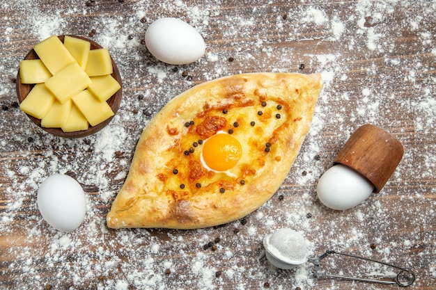 Vue de dessus du pain aux œufs cuits au four avec de la farine sur la surface brune de la pâte de pain aux œufs petit-déjeuner