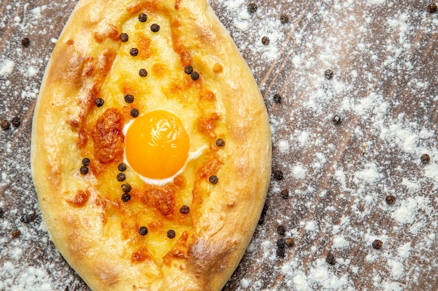 Vue de dessus du pain cuit au four avec des œufs cuits et de la farine sur la surface brune de la pâte de pain aux œufs petit-déjeuner