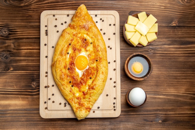 Vue de dessus du pain frais cuit au four avec oeuf cuit sur une pâte de bureau brun alimentaire petit déjeuner cuire petit pain