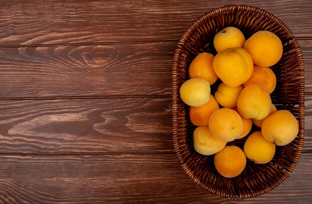 Vue de dessus du panier d'abricots sur fond en bois avec espace copie