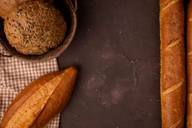 Vue de dessus du panier d'épis ensemencés sur tissu et baguettes sur fond marron avec copie espace