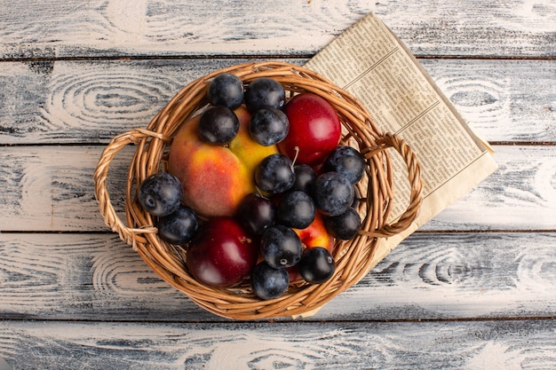 Vue De Dessus Du Panier Avec Prunes, Pêches Et Prunes Sur Le Bureau Gris