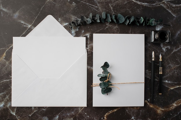 Photo gratuite vue de dessus du papier de mariage et de l'enveloppe avec des plantes séchées