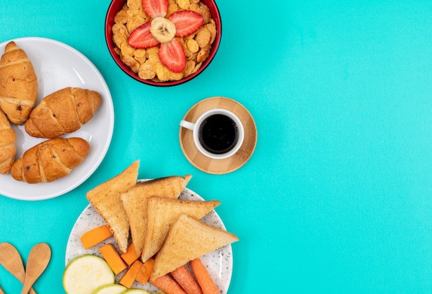 Vue de dessus du petit déjeuner avec croissants, toasts et café avec copie espace sur fond bleu horizontal