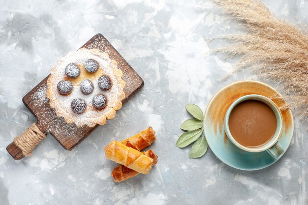 Vue de dessus du petit gâteau avec des frutis et du sucre en poudre avec des bracelets et du lait sur la lumière, gâteau biscuit sucré sucré