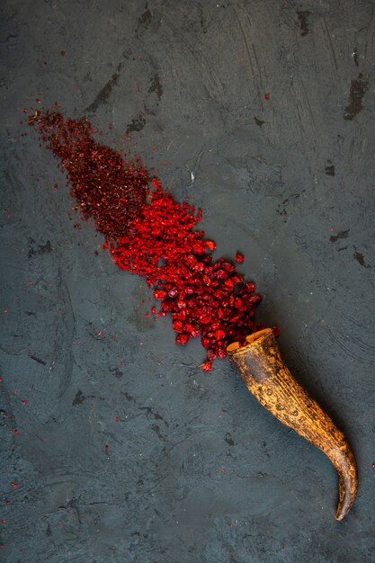 Vue de dessus du piment rouge et de la poudre de sumac sur fond noir