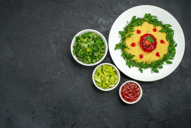 Vue de dessus du plat de pommes de terre en purée avec sauce tomate et légumes verts sur noir