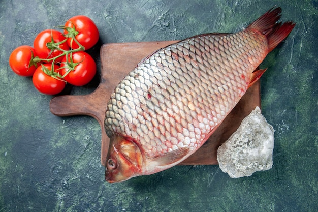 Photo gratuite vue de dessus du poisson cru frais sur une planche à découper fond bleu foncé