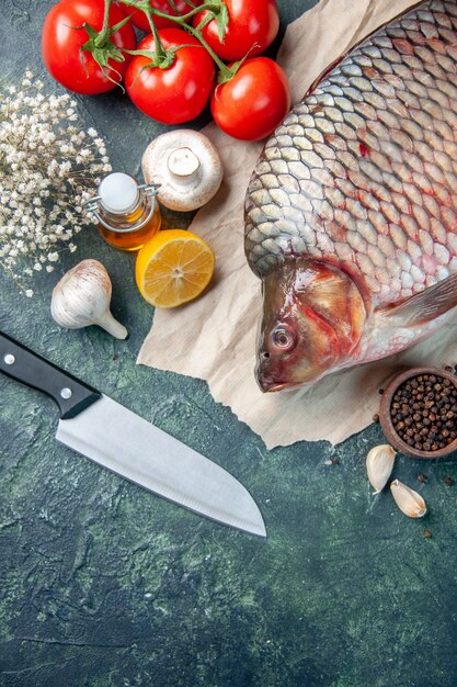 Vue de dessus du poisson cru frais avec des tomates rouges et des champignons sur fond bleu foncé