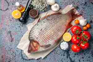 Photo gratuite vue de dessus du poisson cru frais avec des tomates rouges sur fond bleu