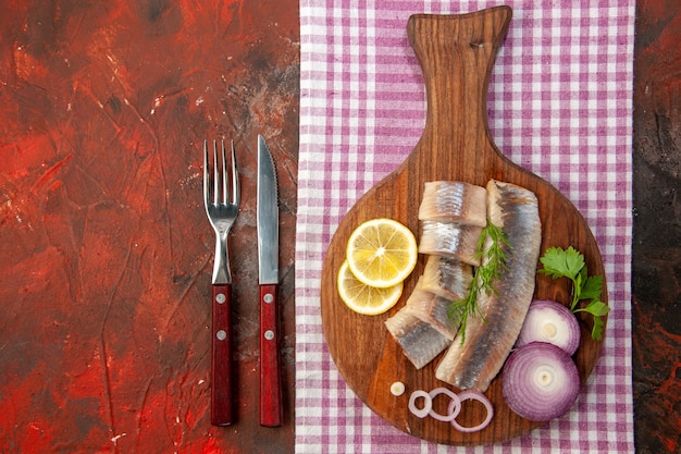 Vue de dessus du poisson cru en tranches avec rondelles d'oignon et citron sur fond sombre