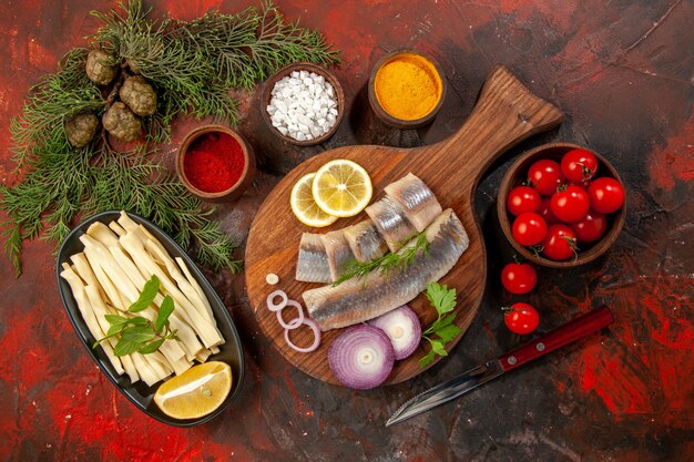 Vue de dessus du poisson frais tranché avec assaisonnements tomates et fromage sur fond sombre