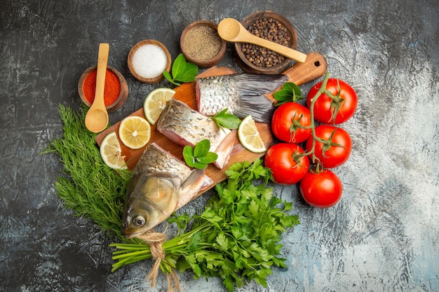 Vue de dessus du poisson frais tranché avec du citron et des verts sur une surface légère