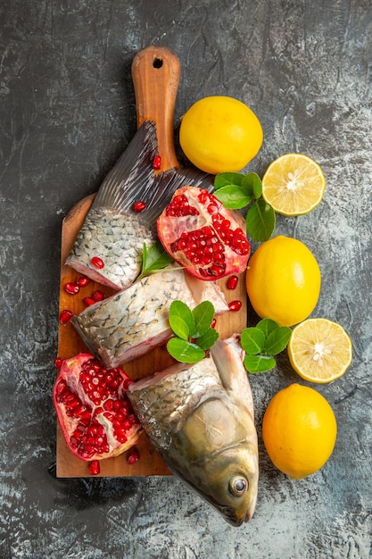 Vue de dessus du poisson frais en tranches avec des grenades et du citron sur une surface légère