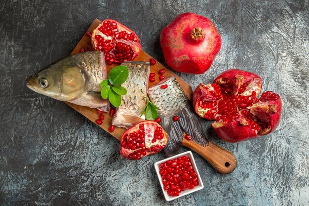 Vue de dessus du poisson frais en tranches avec des grenades sur une surface clair-sombre