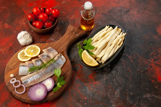 Vue de dessus du poisson frais en tranches avec des rondelles d'oignon, du fromage et des tomates sur fond sombre