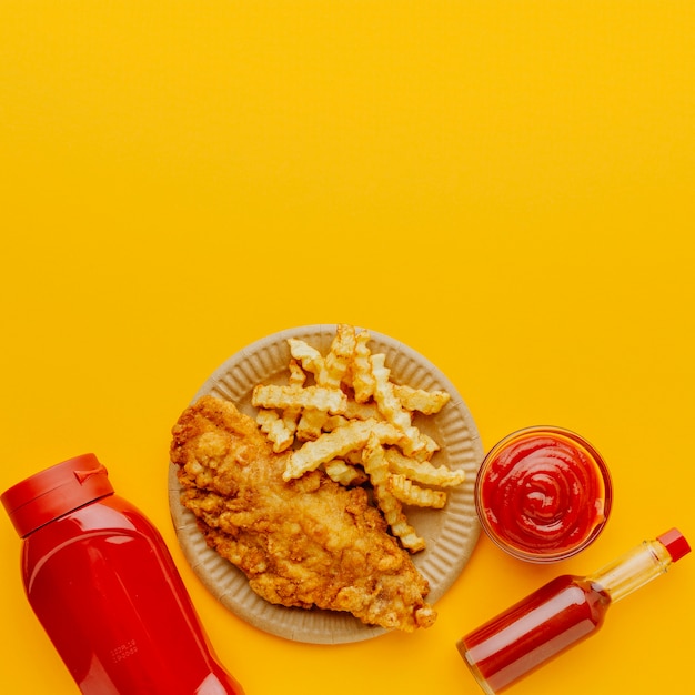 Photo gratuite vue de dessus du poisson-frites avec des bouteilles de ketchup