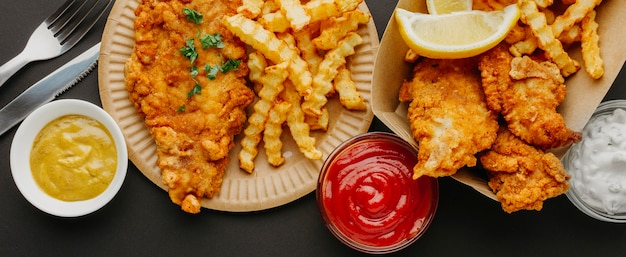 Vue de dessus du poisson-frites avec sélection de sauces et couverts