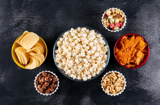 Vue de dessus du pop-corn et des chips dans des bols sur horizontal noir