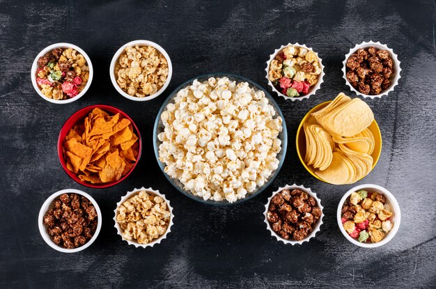 Vue de dessus du pop-corn et des chips dans des bols sur horizontal noir