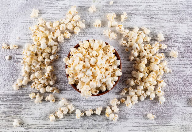 Vue de dessus du pop-corn dans un bol sur l'horizontale en bois blanc