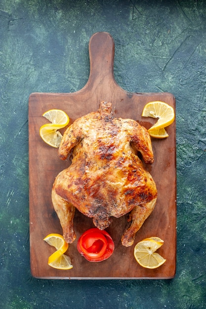 Photo gratuite vue de dessus du poulet épicé cuit au citron sur une surface sombre