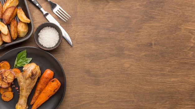 Vue de dessus du poulet et des légumes cuits au four sur une assiette avec des quartiers et un espace copie