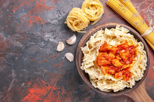 Vue de dessus du poulet avec un plat de pâtes de pâte sur la surface sombre de la pâte de plat de pâtes foncées