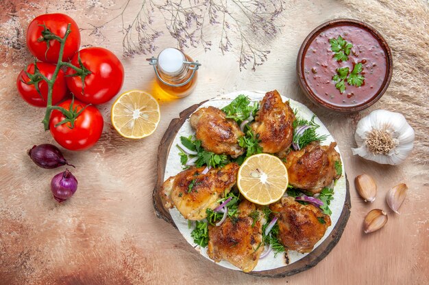 Vue de dessus du poulet tomates oignon poulet aux herbes huile de citron en bouteille de sauce à l'ail