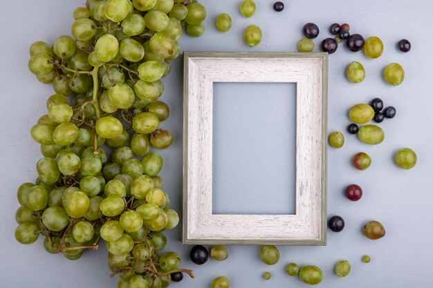 Vue de dessus du raisin blanc et cadre avec des baies de raisin sur fond gris avec espace copie