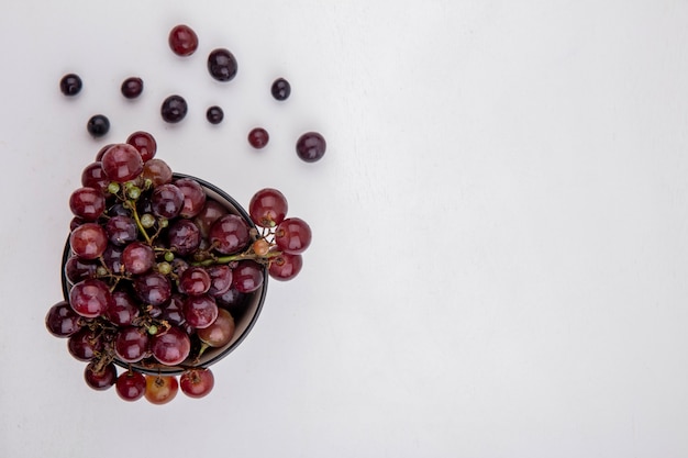 Photo gratuite vue de dessus du raisin rouge dans un bol et sur fond blanc avec espace copie