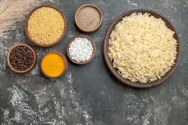 Vue de dessus du riz blanc bouilli et non cuit et de différentes épices