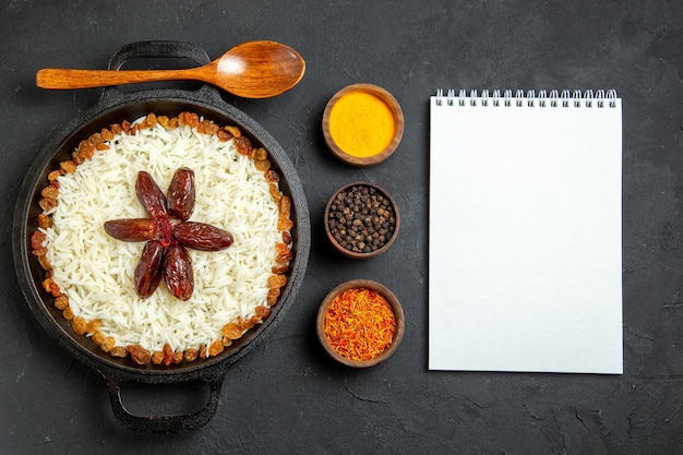 Vue de dessus du riz cuit avec des assaisonnements et des raisins secs sur une surface sombre repas alimentaire riz dîner oriental