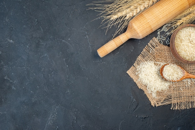 Photo gratuite vue de dessus du riz dans un bol et un rouleau à pâtisserie en bois sur une table avec un espace libre