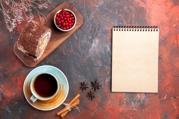 Vue de dessus du rouleau de biscuit avec une tasse de thé sur une surface sombre